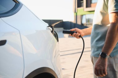 Şarj kablosunu açık hava şarj istasyonundaki elektrikli araca bağlayan sürücüye yakın çekim