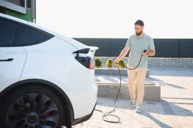 Sürücü güç kaynağı kablosu prize takıldı, Tesla Model Y 'yi şarj etmeye hazırlanıyor