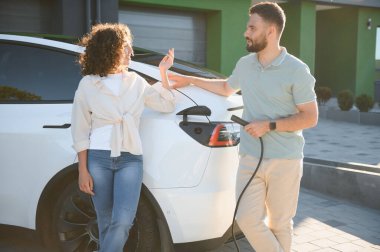 Kabloyu elektrikli araca bağlayan çift, çevre dostu ulaşımı ve modern yaşam için yenilenebilir enerji çözümlerini teşvik ediyor