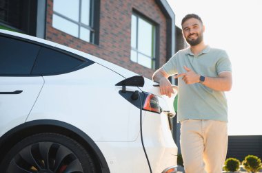 Güler yüzlü adam güneşli bir günde elektrikli araç yüklüyor.