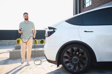 Tesla Model Y 'yi şarj ederken elinde kablo tutan adam