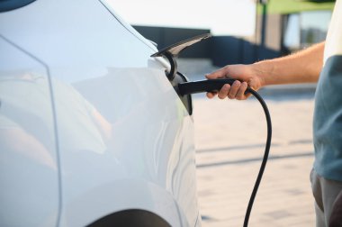 İstasyonda şarj edilen elektrikli arabaya takılı güç kablosu yerleştirme