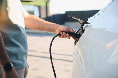 İstasyonda şarj edilen elektrikli arabaya takılı güç kablosu yerleştirme