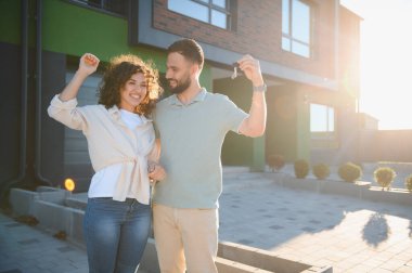 Genç ev sahipleri sevinçle yeni bir mülk satın alarak, anahtarlarını tutarak ve geleceklerini kucaklayarak elde ettikleri heyecan verici başarıyı kutluyorlar.