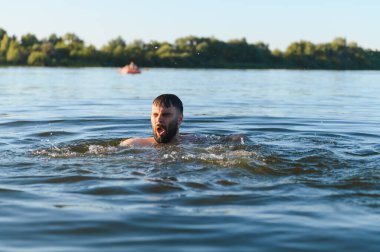 Yaz tatili boyunca nehirde boğulan sakallı bir adam çaresizce yardım ve nefes almak için haykırıyor.