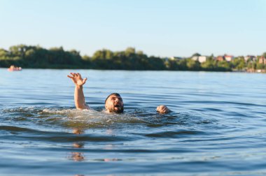 Bir yaz öğleden sonra gölde boğulan genç adam elini kaldırıyor ve bağırıyor, yardım istiyor.