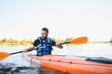 İnsanoğlu serin bir nehirde kanoyla kürek çekiyor, çarpıcı doğayla çevrili, su sporlarının ve aktif açık hava eğlencelerinin neşesini kucaklıyor.