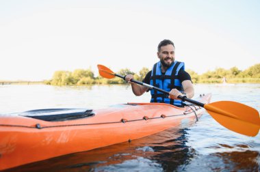 Adam sakin bir nehirde kanoya biniyor, doğa güzelliğinin tadını çıkarırken açık hava eğlencesi ve macera peşinde koşuyor.