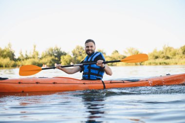 Can yelekli bir adam, güneşli bir günde gölde kayak yapıyor, aktif eğlence ve su sporlarının tadını çıkarıyor.