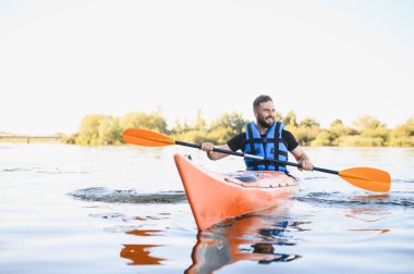 Can yelekli bir adam nehirde kayak yapıyor, güneşli bir günde su sporları ve aktif eğlence yapıyor.