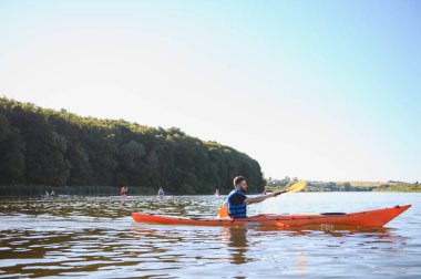Kanocu sakin bir gölde kürek çeker, doğanın huzuru ve su sporlarının heyecanıyla eğlenir.