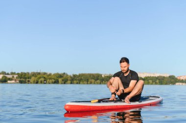 Genç sporcu yemek masasında oturmuş güneşli bir gökyüzünün altındaki dingin gölde heyecanlı bir kürek macerasına hazırlanıyor.
