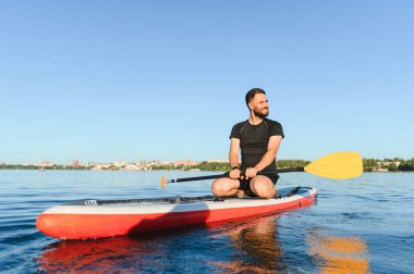 Genç sporcu yemek masasında oturuyor, göldeki eğitimden sonra şehir manzarasının tadını çıkarıyor.