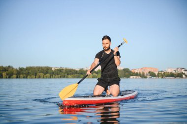 Genç sporcu, yemek masasında diz çökmüş gölde güneşli bir günün tadını çıkarıyor.
