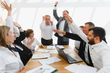 Üretken bir ofis toplantısında başarılı bir sonucu kutlayan hevesli bir iş ekibi.