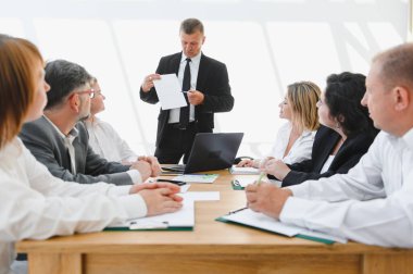 Üst düzey yönetici şirket toplantısında iş stratejisini açıklıyor, verileri gösteriyor ve takım üyeleriyle bağlantı kuruyor.