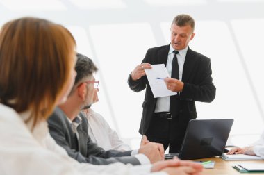 İşletme ekibi üst düzey bir yöneticiyi dinlemekle meşgul. Ofisteki bir toplantıda istatistikleri anlatıyor.