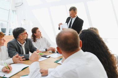 Üst düzey yönetici, modern ofiste şirket toplantısında iş stratejisini ekibe sunuyor, işbirliği ve başarıyı teşvik ediyor.