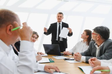 Tecrübeli yönetici iş planını ekibe sunar, işbirliğini teşvik eder ve modern ofis ortamında başarılı olur.