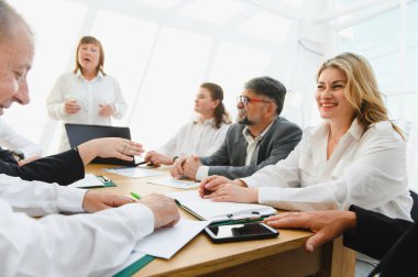 İşbirliği yapan, beyin fırtınası yapan ve şirket amaçlarına ulaşmak için verimli bir toplantıya katılan profesyoneller.