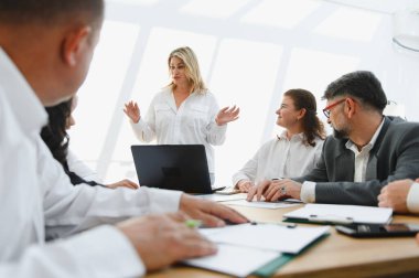 Kadın yönetici, modern bir ofiste verimli bir toplantı sırasında iş ekibine yeni bir strateji anlatıyor.