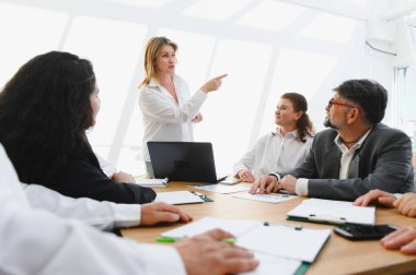 Takım lideri şirket toplantısında iş stratejisini açıklıyor, gelecekteki hedeflerine işaret ediyor ve ekibine ilham veriyor.