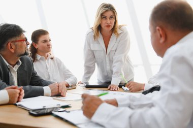 İş dünyası ekibi, azimli bir kadın liderin rehberliğinde bir toplantı sırasında stratejik bir tartışmaya girişiyor.