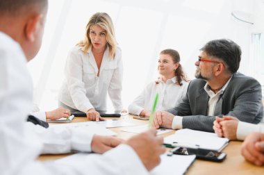 Verimli bir toplantı sırasında verileri analiz eden ve işbirliği yapan bir iş adamı ve tartışmayı yöneten bir kadın lider.