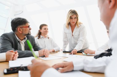 Ekonomik tabloları ve raporları analiz eden iş ekibi, verimli bir ofis toplantısında proje geliştirme konusunda işbirliği yapıyor