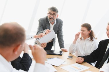 Üretken bir ofis toplantısında proje üzerinde işbirliği yapan iş ekibi, stratejileri tartışıyor ve belgeleri analiz ediyor