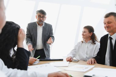 Deneyimli yönetici çeşitli takım üyeleriyle verimli bir iş toplantısı yapıyor, stratejileri tartışıyor ve birlikte başarı elde ediyor.