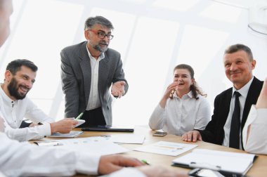 İş adamları, liderleriyle başarılı bir toplantı yaparak gülüyor ve eğleniyorlar, olumlu sonuçları ve başarıları kutluyorlar.