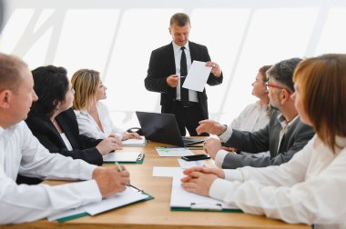 Üst düzey yönetici bir şirket toplantısı sırasında takıma bir proje sunuyor. Stratejik görüşleri tartışıyor ve sergiliyor.