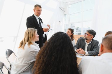 Parlak ve modern bir ofiste, liderleriyle verimli bir toplantı yaparak işbirliği ve stratejik planlamayı teşvik eden iş adamları.