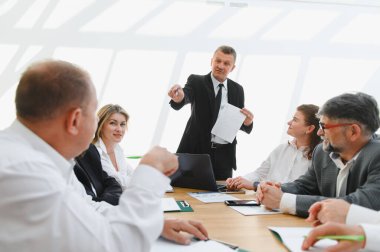 Üst düzey yönetici, modern bir ofiste yapılan şirket toplantısında iş stratejisini meslektaşlarına anlatıyor.