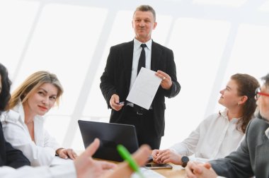 Parlak bir ofiste, verimli bir toplantı sırasında takım çalışması ve işbirliği yapan bir proje üzerinde birlikte çalışan iş adamları.