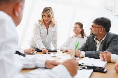 Modern bir ofiste verimli bir toplantı sırasında iş adamları birlikte çalışır, verileri analiz eder ve stratejiyi tartışırlar.