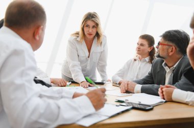 Kararlı bir kadın liderin önderliğindeki toplantı sırasında iş adamları, başarı için birlikte çalışırlar.