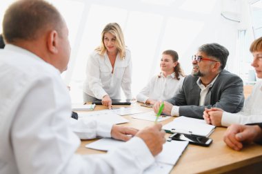 Bir şirket toplantısında verileri tartışıp analiz eden iş adamları, işbirliği ve stratejik karar alma üzerine odaklanırlar.