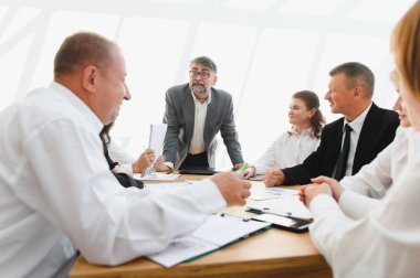 İş ekibi, ilham verici bir lider tarafından yönetilen, işbirliğini teşvik eden ve işyerinde başarıyı yönlendiren verimli bir toplantıya girişiyor.