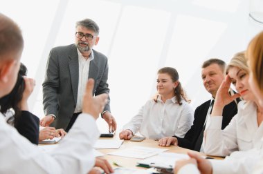 İş adamları, modern bir ofiste yaptıkları dinamik toplantıda liderleriyle iletişim kurarak işbirliği ve stratejik planlamayı destekliyor.