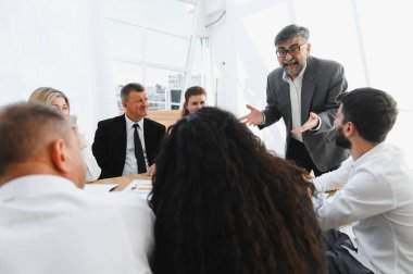 Üretken bir toplantıya liderlik eden deneyimli bir yönetici, iş arkadaşlarıyla yakınlaşıyor ve başarı için işbirliğini teşvik ediyor