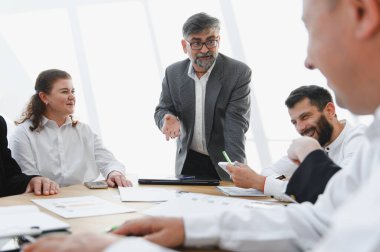 Kıdemli iş adamı, verimli bir toplantıda ekibine ilham veriyor, işbirliğini teşvik ediyor ve birlikte başarı elde ediyor.