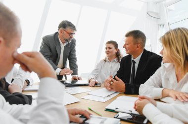 Şirket toplantısında işbirliği yapan ve stratejiyi tartışan iş adamları takım çalışmasını teşvik ediyor ve başarıyı hedefliyor.