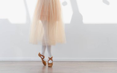 Bale ayakkabısı ve etek giyen balerin kız dans okulu stüdyosunda bale çalışıyor.