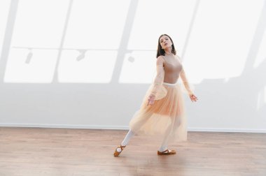 Genç balerin dans figürlerini güneşli bir stüdyoda çalışıyor. Zarafet, duruş ve sanatına olan bağlılığını sergiliyor.