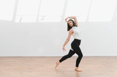 Modern koreografiyi parlak bir stüdyoda icra eden zarif bir dansçı, çağdaş dans yoluyla sanatsal ve hareketli olduğunu ifade ediyor.