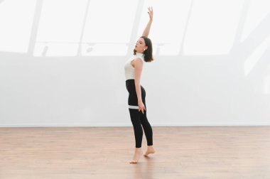 Parlak bir stüdyoda modern bir dans gösterisi sergileyen zarif dansçı esneklik, beceri ve sanatsal ifade sergiliyor.