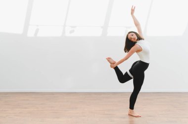 Çağdaş dans koreografisini parlak bir stüdyoda uygulayan kadın dansçı esneklik ve sanatsal ifade sergiliyor.