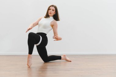 Parlak bir stüdyoda modern dans figürleri sergileyen zarif bir dansçı. Esneklik ve sanatsal ifade sergiliyor.